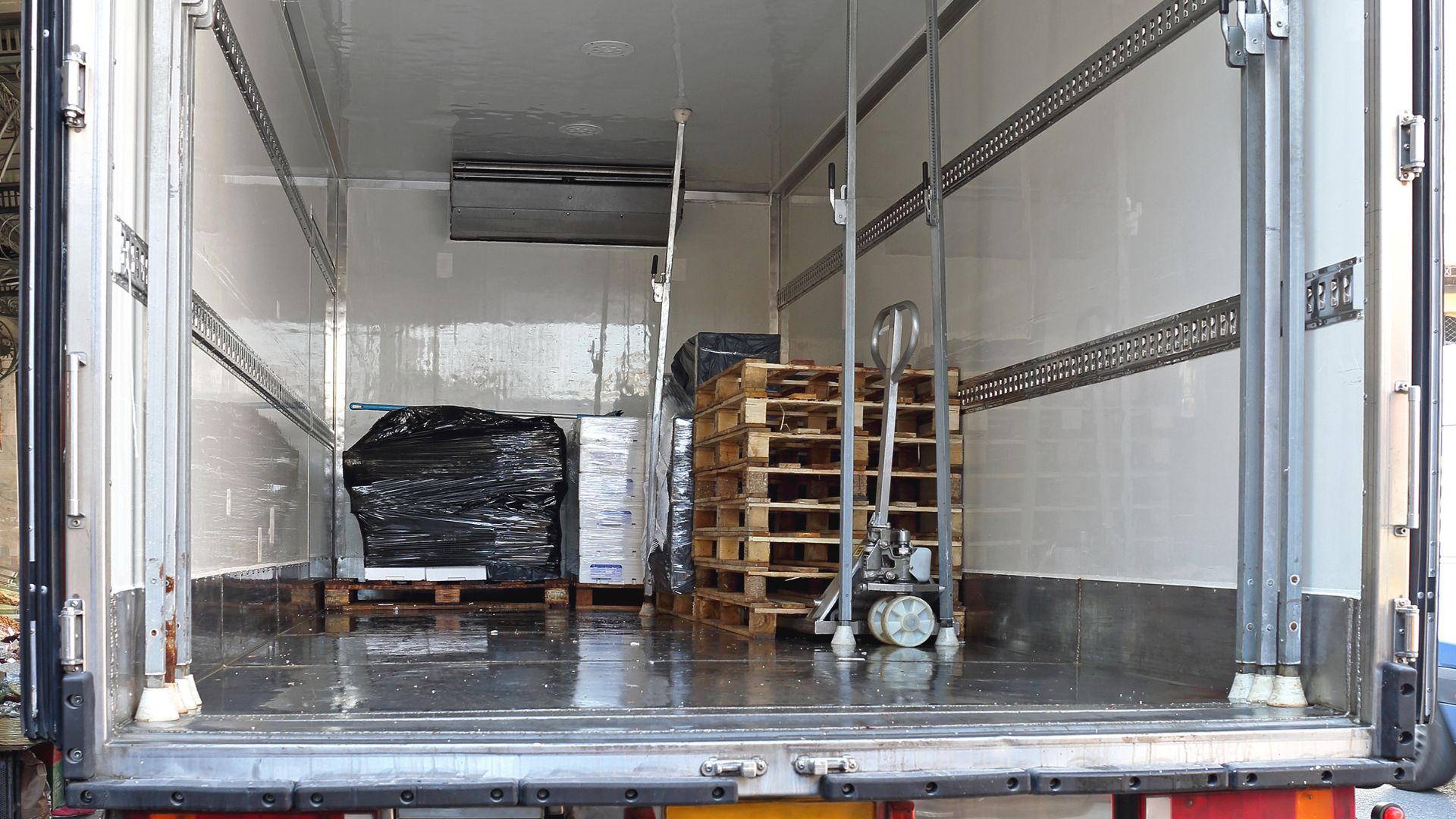 Se observa el interior de una caja refrigerada, la cual contiene múltiples elementos de estabilidad de carga como pallets y barras.